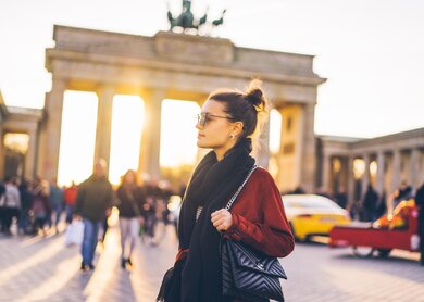 Frau vor Brandenburger Tor Berlin | © Gettyimages.com/Xsandra Portrait einer jungen Frau vor dem Brandenburger Tor in Berlin | © Gettyimages.com/Xsandra
