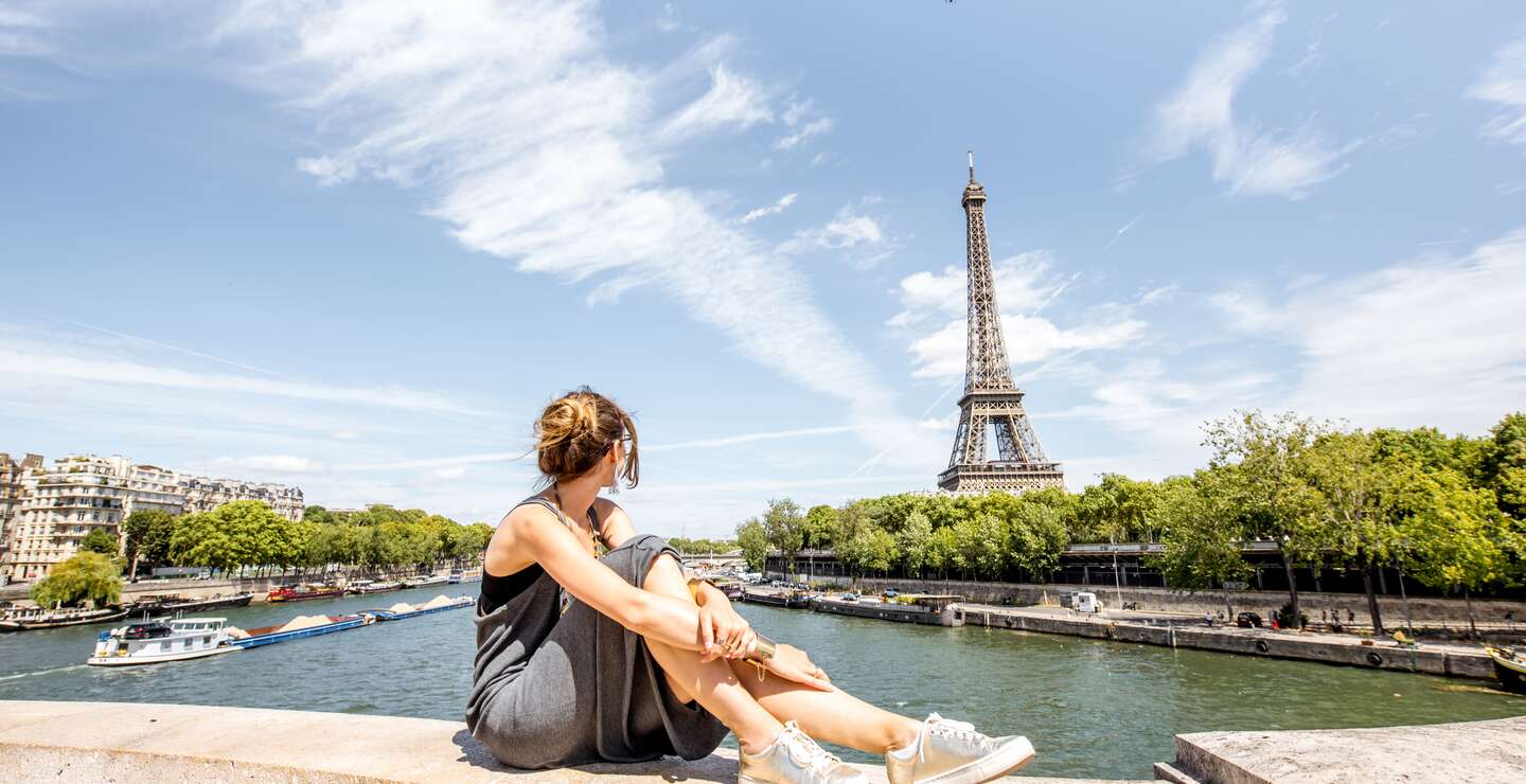 Frau vor dem Eiffelturm in Paris | © Gettyimages.com/RossHelen Junge stilvolle Frau mit herrlichem Blick auf den Eiffelturm auf der Brücke in Paris | © Gettyimages.com/RossHelen
