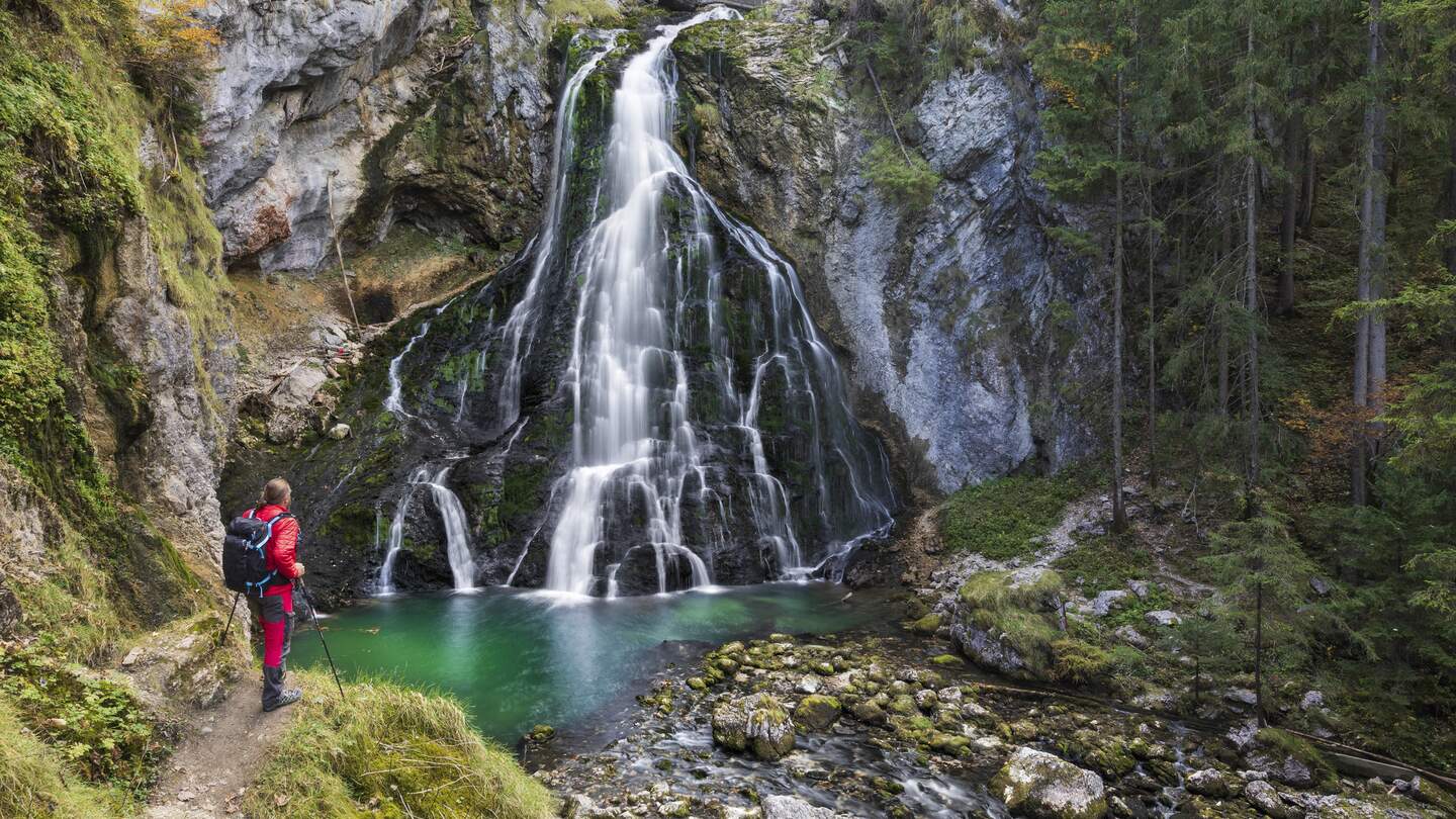 Männliche Wanderer am idyllischen Wasserfall Szene mit bemoosten Felsen im Wald  | © Gettyimages.com/dietermeyrl