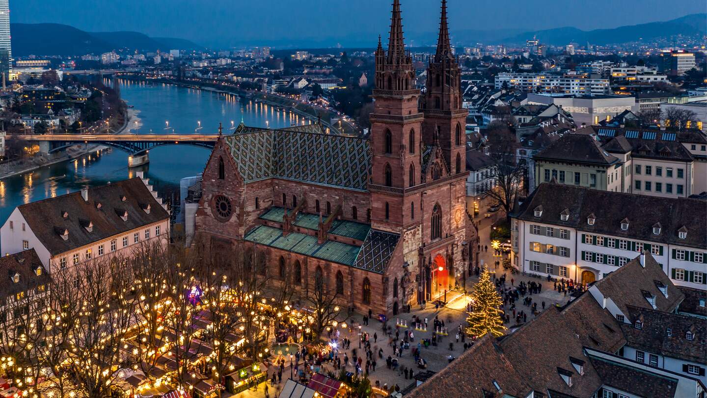 Weihnachtsmarkt mit beleuchtetem Münster von Oben | © Schwitzerland Tourismus/Jan Geerk Winterlicher Weihnachtsmarkt mit beleuchtetem Dom und Fluss im Hintergrund | © Schwitzerland Tourismus/Jan Geerk