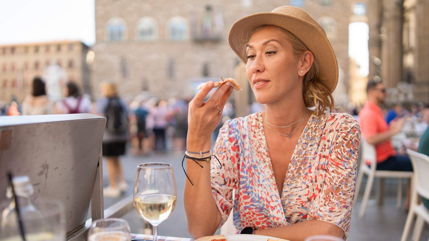 Frau beim Pizzaessen | © Gettyimages.com/	valentinrussanov Frau probiert Pizza in einem italienischen Restaurant im Freien | © Gettyimages.com/	valentinrussanov
