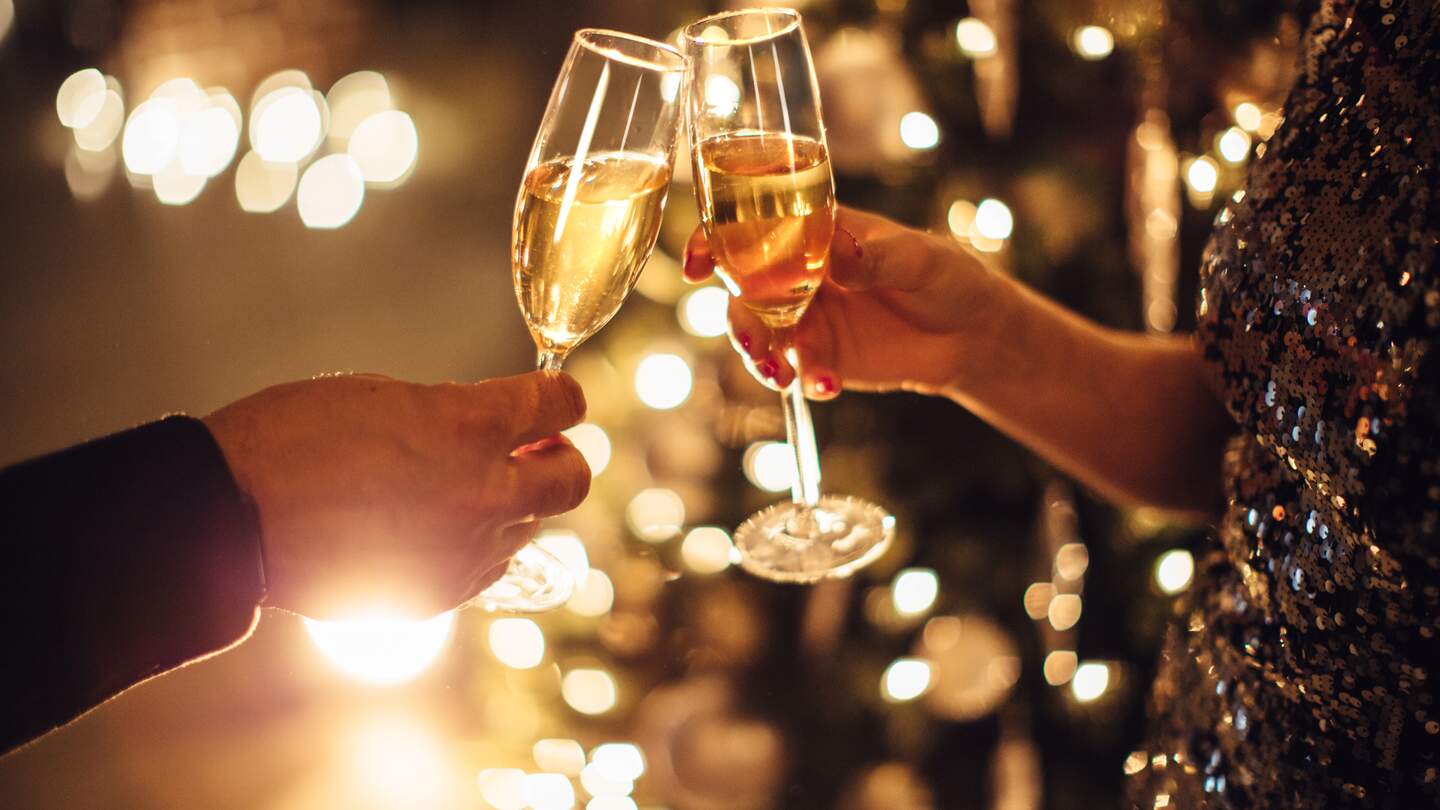 Feiern Sie mit Sekt | © Gettyimages.com/svetikd Paar haelt Glaeser Champagner vor dem Weihnachtsbaum | © Gettyimages.com/svetikd