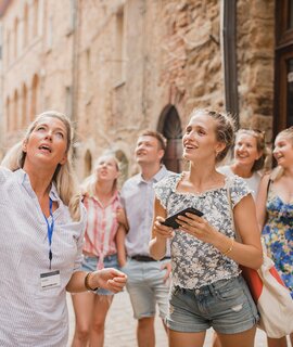 Historischer, geführter Stadtrundgang einer kleinen Reisegruppe | © Gettyimages.com/SolStock Kleine Reisegruppe auf historischem Stadtrundgang. Sie hoert einem Reiseleiter zu, der ueber die Architektur und die Geschichte spricht. | © Gettyimages.com/SolStock