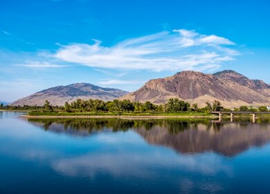 Thomson River, Kamloops, BC mit Bergkette und Eisenbahnbrücke in der Ferne. | © GettyImages.com/BriBar