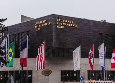 Deutsche Auswandererhaus in Bremerhaven mit Fahnen vor der dem Museum | © Gettyimages.com/Wirestock