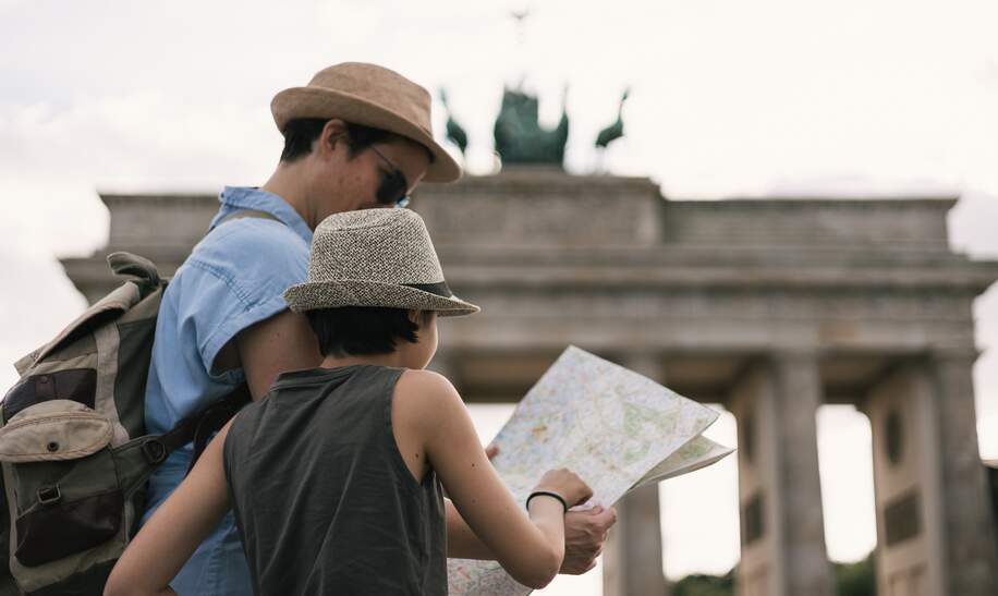 Elternteil mit Kind schaut auf eine Karte am Brandenburger Tor in Berlin | © Gettyimages.com/Amparo Garcia V