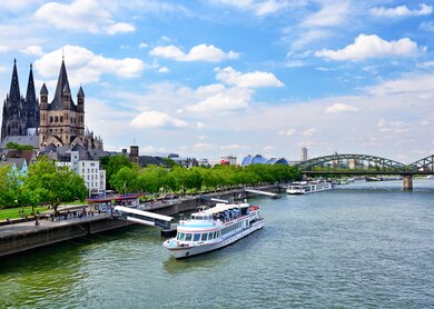 An der Rheinpromenade in Köln legt ein Boot an. Im Hintergrund ist der Kölner Dom zu sehen. | © Gettyimages.com/alxpin