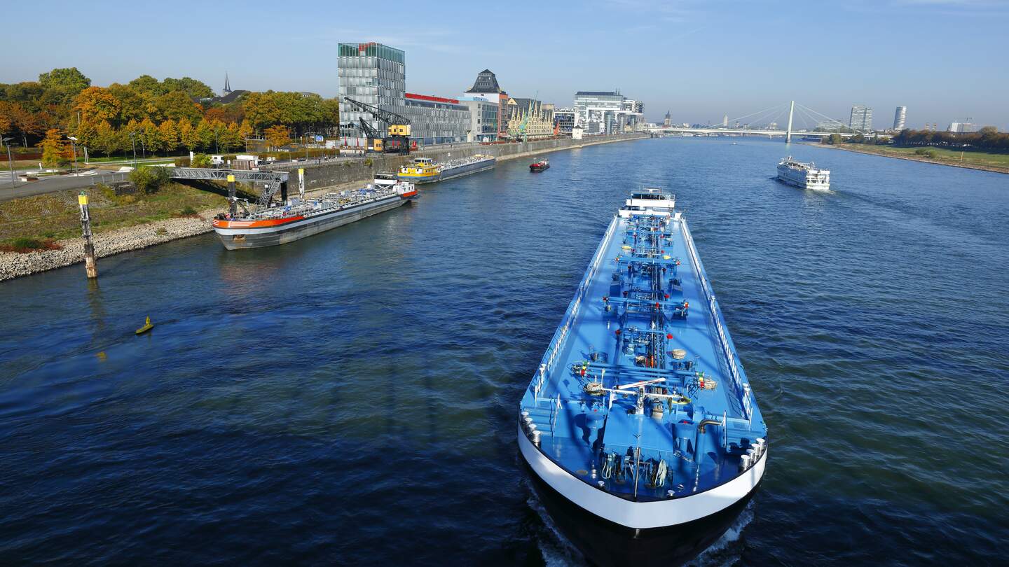 Aufsicht auf ein Schiff am Rheinauhafen in Köln mit Passagieren bei hellblauem Himmel | © Gettyimages.com/horstgerlach