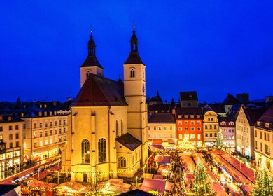 Erhöhter Blick auf den Regensburger Weihnachtsmarkt mit Essens- und Weihnachtsdekorationsständen rund um die 500 Jahre alte Neupfarrer Kirche und schönen Häusern. | © Gettyimages.com/Juergen Sack