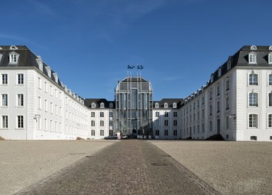 Das Schloss Saarbrücken ist im Barockstil erbaut. Vor dem Gebäude bereiten einige Leute eine Veranstaltung vor. | © Gettyimages.com/kontrast-fotodesign