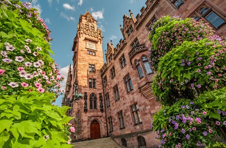 Untersicht auf das Rathausgebäude in der Saarbrücken, Saarland, das Touristische und Reise-Wahrzeichen im Frühling mit Blumen | © Gettyimages.com/frantic00