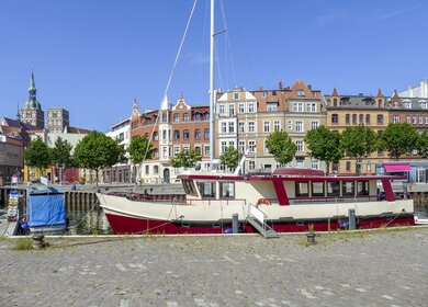 Idyllische, sonnige Hafenlandschaft in der Hansestadt Stralsund mit einem Boot im Vordergrund | © Gettyimages.com/prill