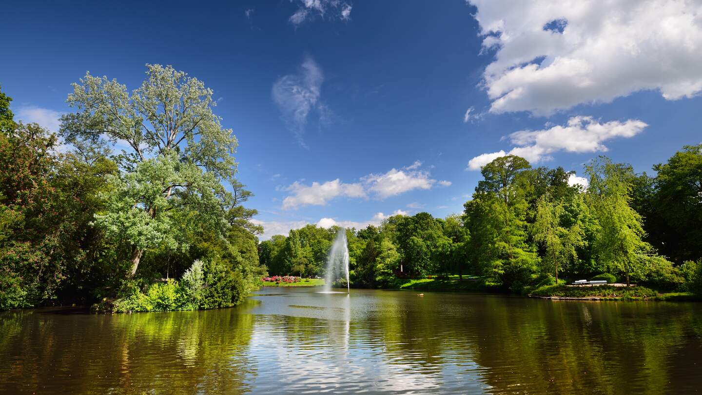 Blick auf einen schönen See mit Springbrunnen in einem grünen blühenden Kurpark in Wiesbaden | © Gettyimages.com/alekseystemmer