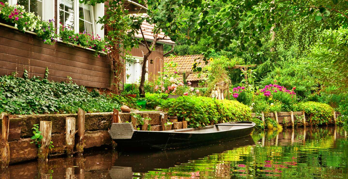 Kleine Ferienhäuser in der Nähe der Spree mit einem Boot auf dem Fluss | © Gettyimages.com/kerrick