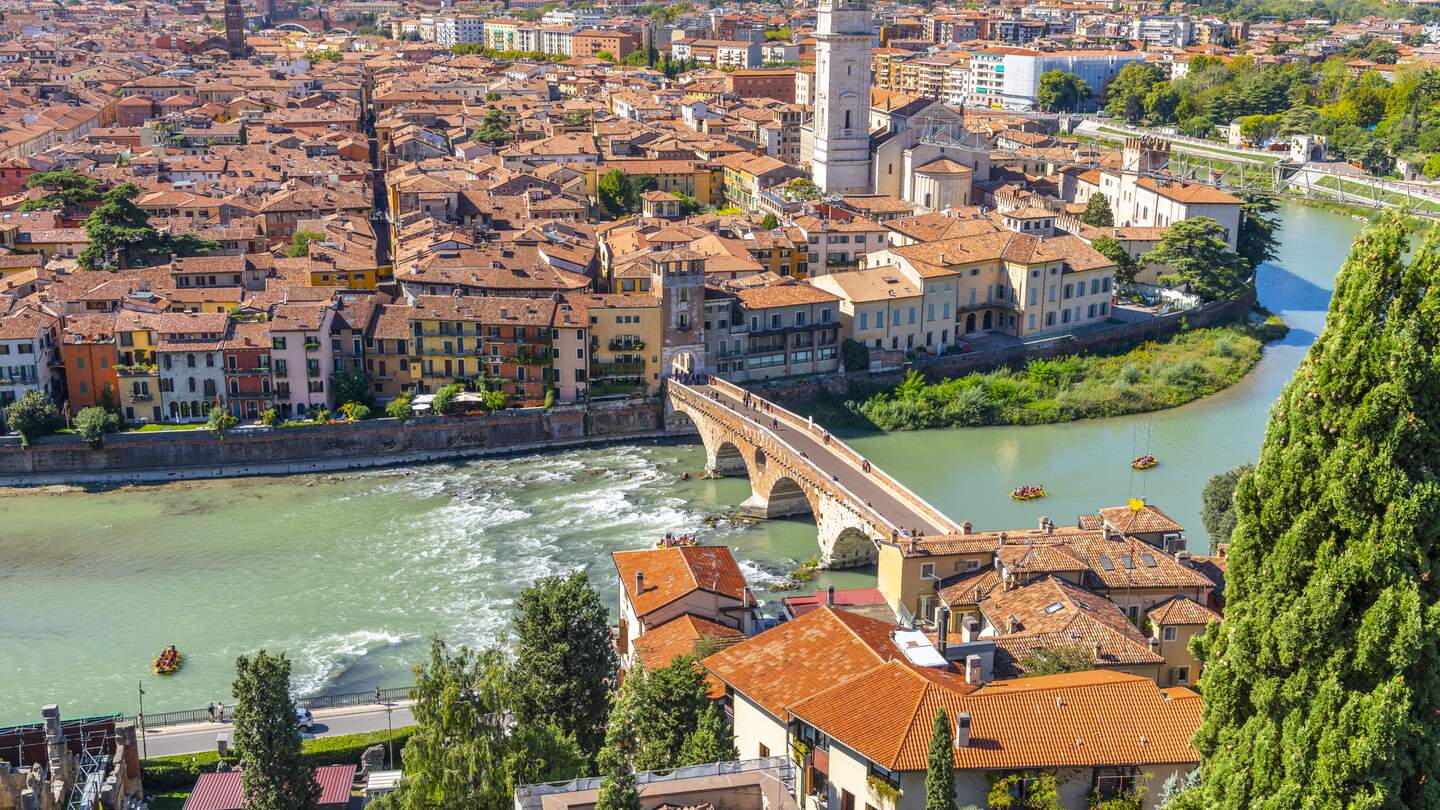Blick auf das historische Zentrum der Stadt Verona, Italien und die Brücke Ponte Pietra und die Etsch von der Hügelfestung Castel San Pietro, mit Gruppen von Flößern, die eine Fahrt auf dem Fluss genießen. v | © Gettyimages.com/kirkfisher