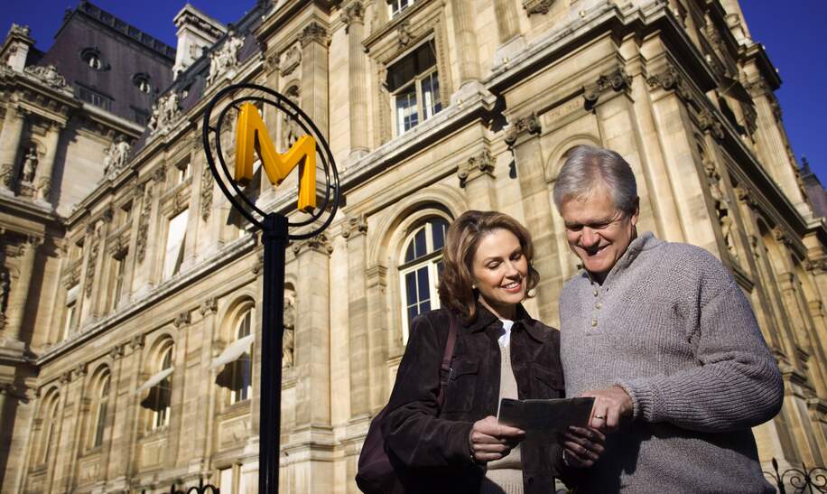 Mann und Frau, die in eine Stadtkarte vor dem Metro-Zeichen in Paris schauen. | © Gettyimages.com/Thinkstock