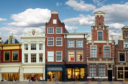 Stadtszene Amsterdam mit liebevoll restaurierten Giebelhäusern und kleinen Ladengeschäften an einer Grachtenbrücke | © Gettyimages.com/MediaProduction