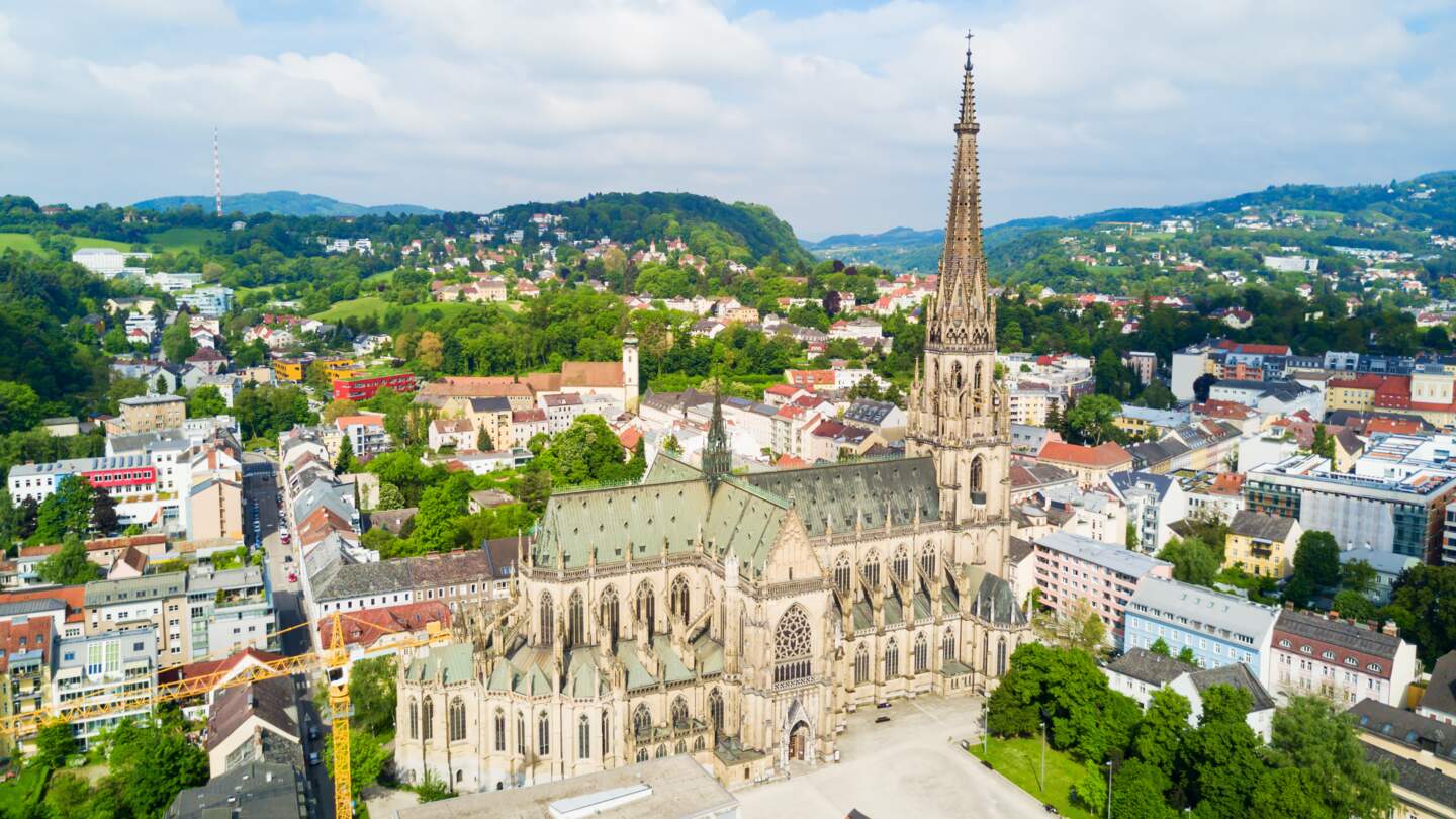 Blick von oben auf die Marienkirche in Linz mit wunderschöner Landschaft | © Gettyimages.com/saiko3p