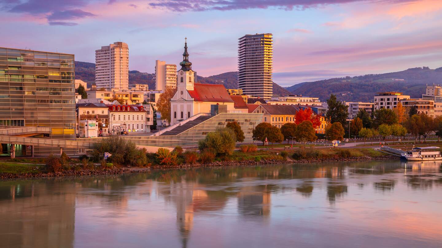 Stadtbild des Flussufers von Linz, Österreich bei wunderschönem Herbstsonnenaufgang mit Spiegelung der Stadt in der Donau | © Gettyimages.com/RudyBalasko
