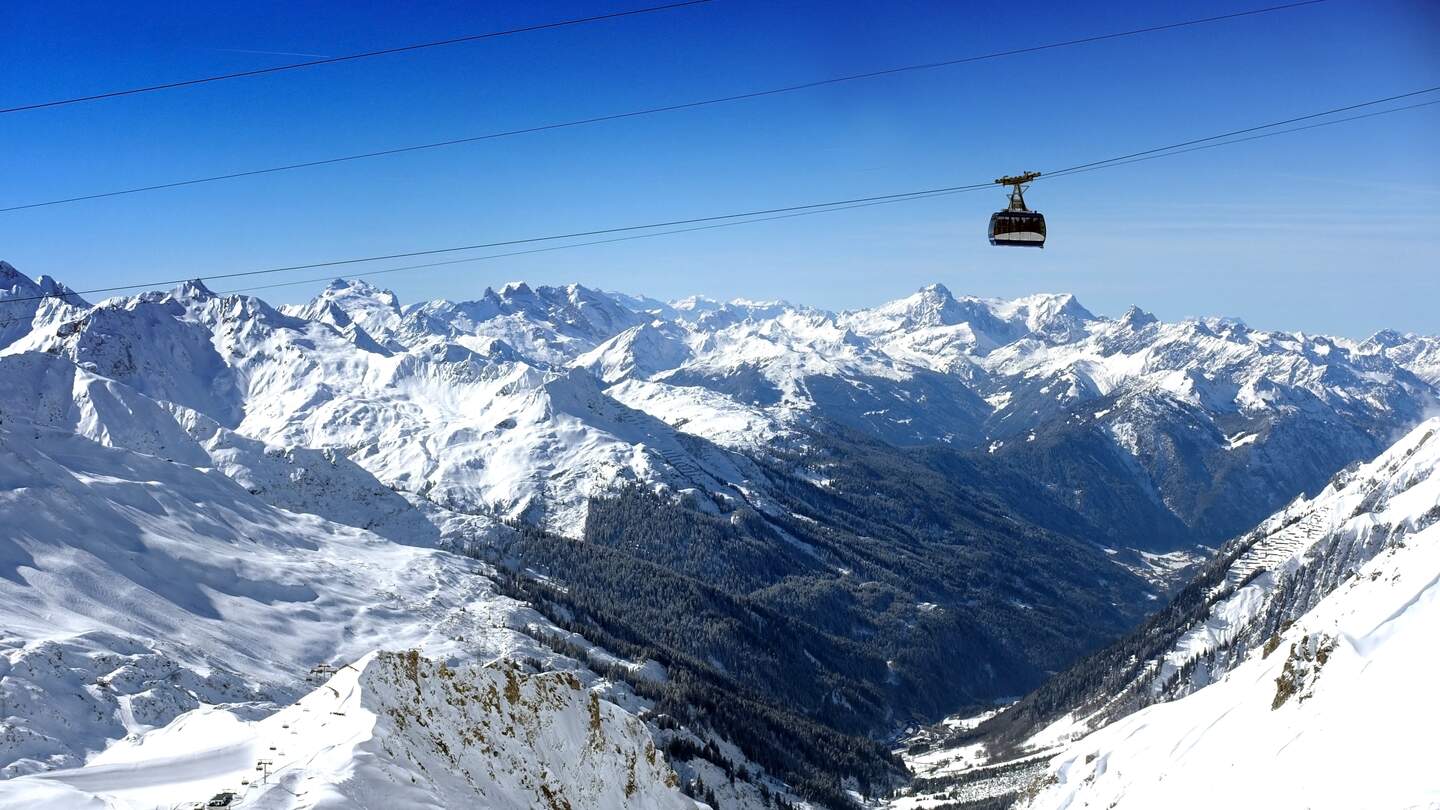 Skilift Valluga Bahn im Skigebiet St. Anton, Österreich, an einem sonnigen Tag, umgeben von schneebedeckten Bergen. | © Gettyimages.com/imagean