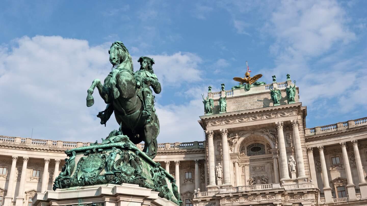 Dramatischer Weitwinkel auf die Hofburg in Wien, mit einer Statue im Vordergrund | © Gettyimages.com/matejphoto
