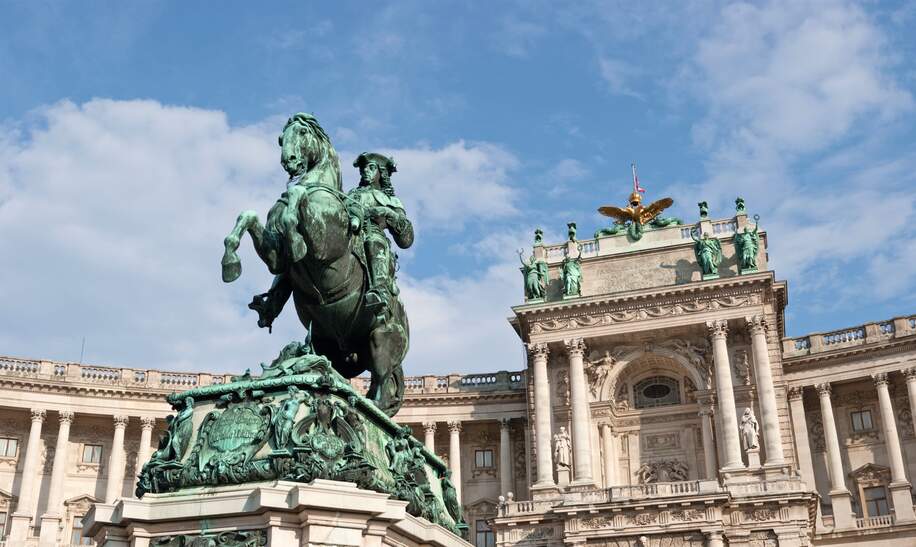 Dramatischer Weitwinkel auf die Hofburg in Wien, mit einer Statue im Vordergrund | © Gettyimages.com/matejphoto