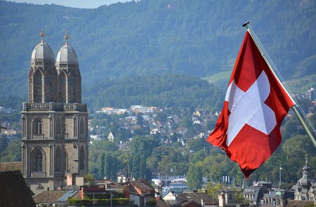 Schweizer Flagge vor der Großmünsterkirche in Zürich | © © Gettyimages.com/lozanona