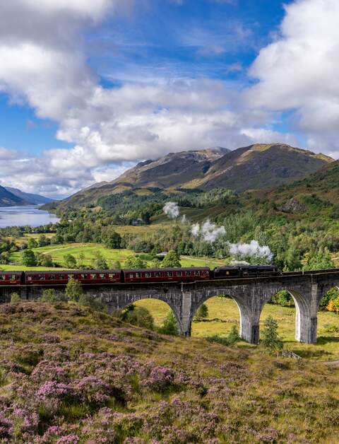 Berühmten Glenfinnan Eisenbahnviadukt in Schottland. Ein Zug fährt gerade über das gigantische Bauwerk mit atemberaubenden Hintergrund | © Gettyimages:com/catuncia