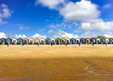 Bunte Strandhäuser am Strand mit Blick aufs Meer | © Gettyimages.com/elenaestelles