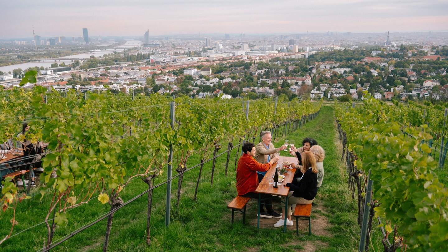 eine Familie stößt auf dem Nussberg zwischen Weinreben an | ©  WienTourismus/Mafalda Rakoš