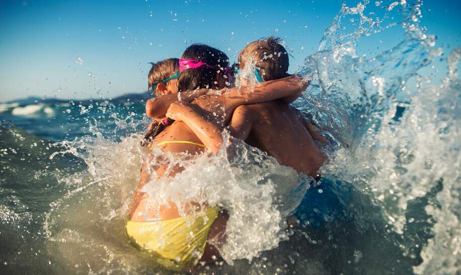 Brüder und Schwester haben Spaß in Meereswellen. Kinder umarmen sich in den Meereswellen. Sonniger Sommertag. | © © Gettyimages.com/Imgorthand