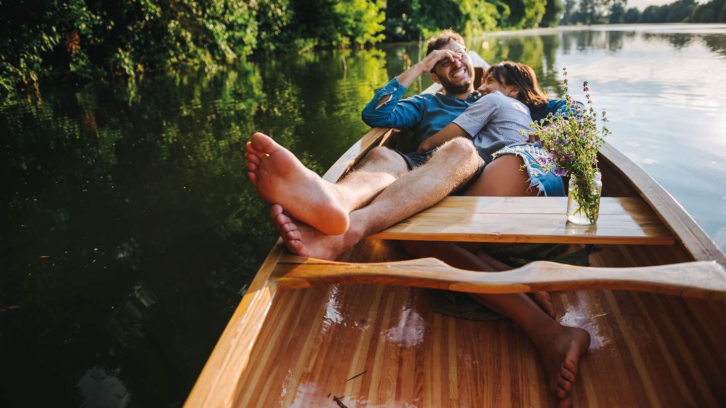 Junges verliebtes Paar entspannt im Ruderboot auf idyllischem See | © Gettyimages.com/Georgijevic