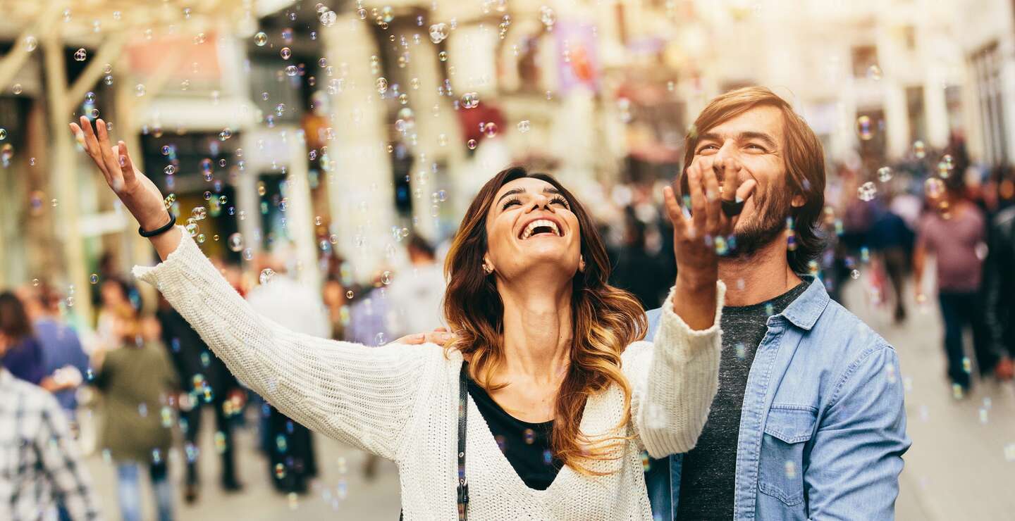 Glückliches junges Paar freut sich an Seifenblasen in der Luft | © Gettyimages.com/filadendron
