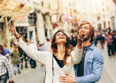 Glückliches junges Paar freut sich an Seifenblasen in der Luft | © Gettyimages.com/filadendron