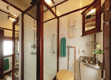Innenansicht des Rovos Rail Deluxe Badezimmers mit Dusche mit Blick auf den Gang | © Rovos Rail Tours