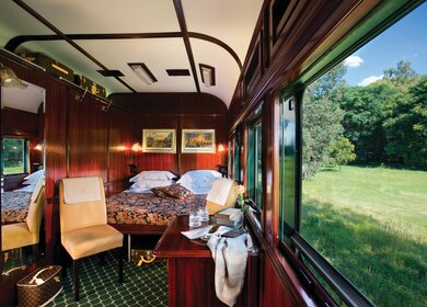 Innenansicht der Rovos Rail Deluxe Suite mit Blick aus dem Fenster mit grüner Landschaft | © Rovos Rail Tours