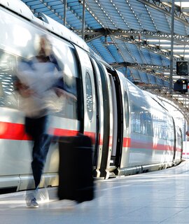 Verschwommene Frau mit Koffer auf dem Bahnsteig mit ICE | © Gettyimages.com/Horst Gerlach