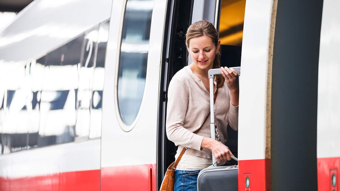 Junge Frau mit Rollkoffer steigt in einen ICE | © Gettyimages.com/ViktorCap