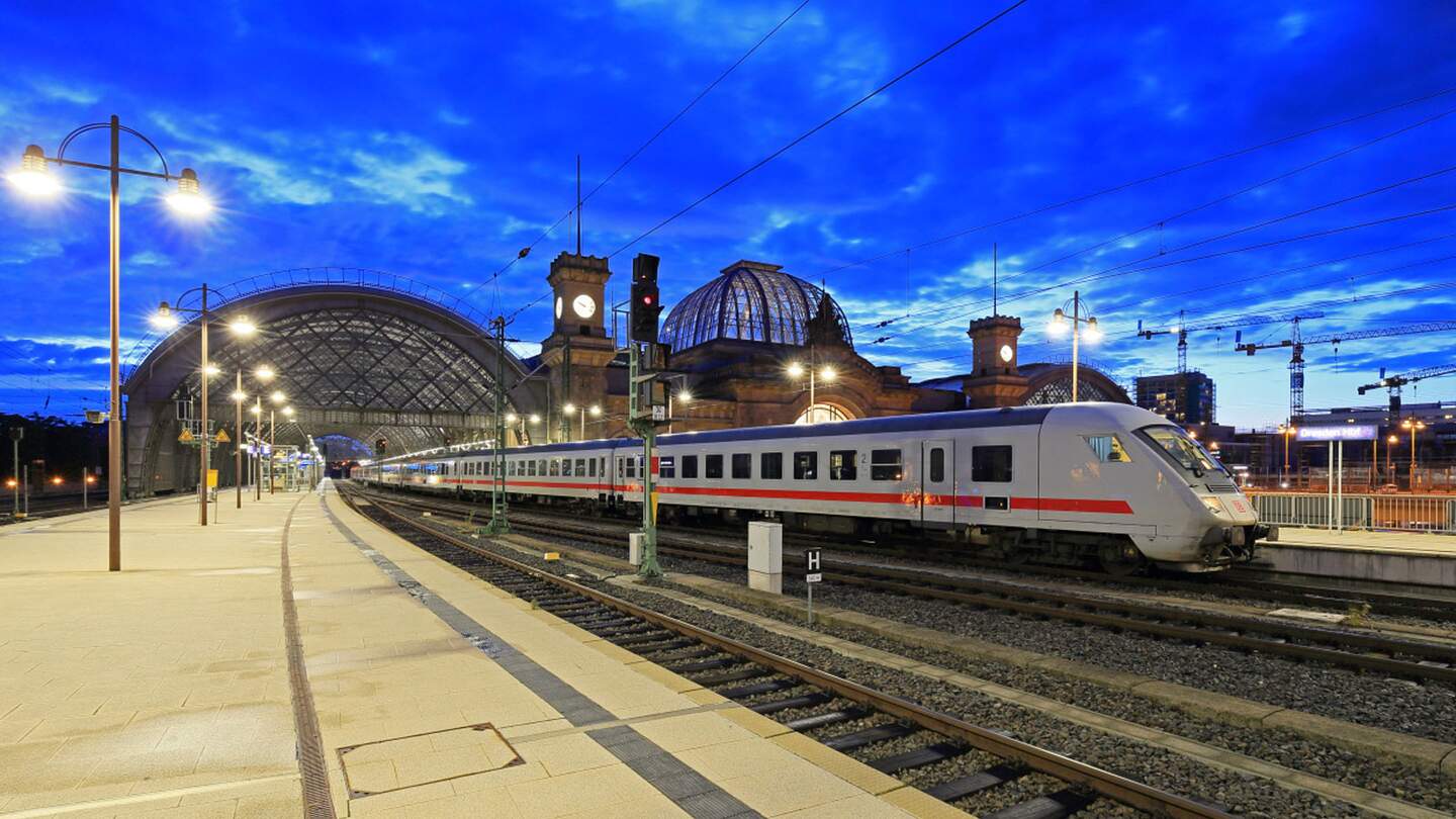 einen Bahnhof bei Daemmerung mit einem einfahrenden oder abfahrenden Zug und einer großen Glasdachkonstruktion. | © Deutsche Bahn AG