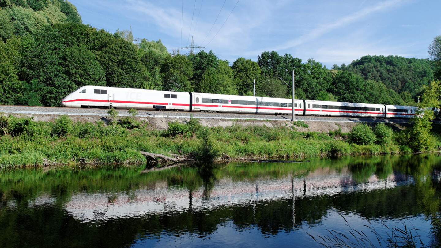 Hochgeschwindigkeitszug mit roten,der entlang von Gleisen neben einem Gewässer fährt.  | ©  Deutsche Bahn AG