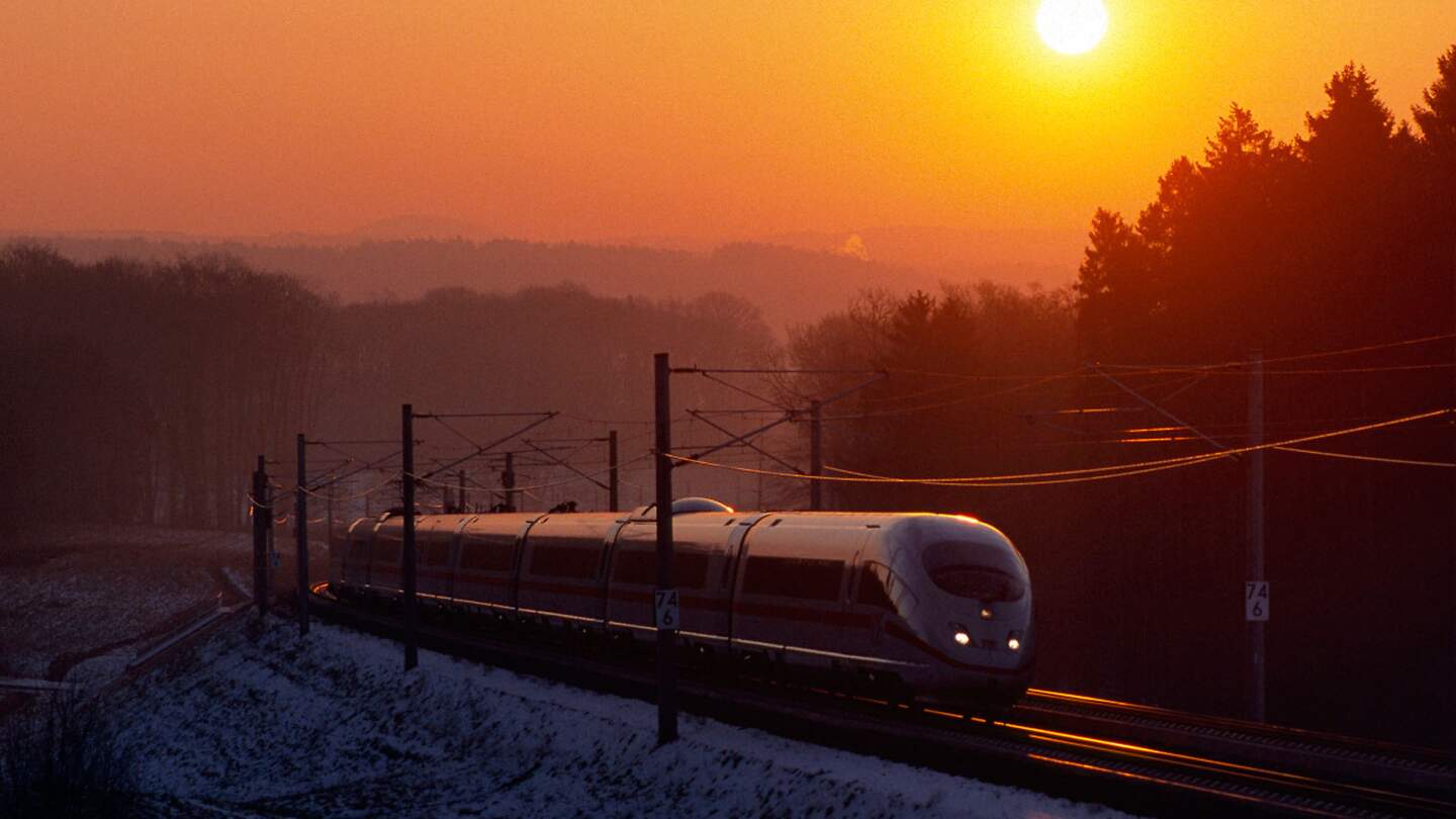 Zug, der bei Sonnenuntergang durch eine verschneite Landschaft fährt | © Deutsche Bahn AG