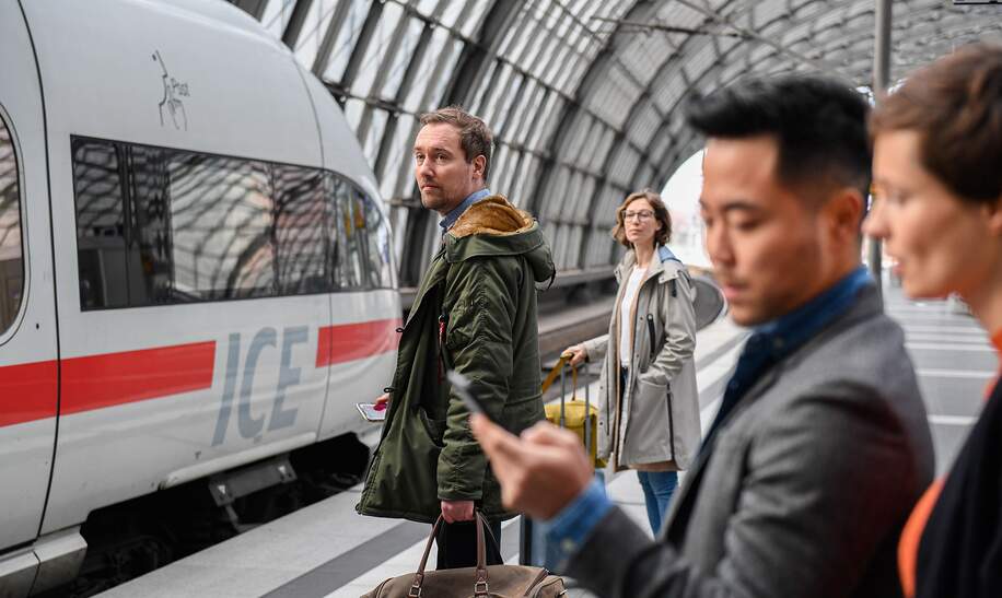 Mehrere Reisende auf dem Bahnsteig im Hauptbahnhof Berlin. Zugeinfahrt und Abfahrtsanzeigetafel. | © Deutsche Bahn AG/Max Lautenschläger