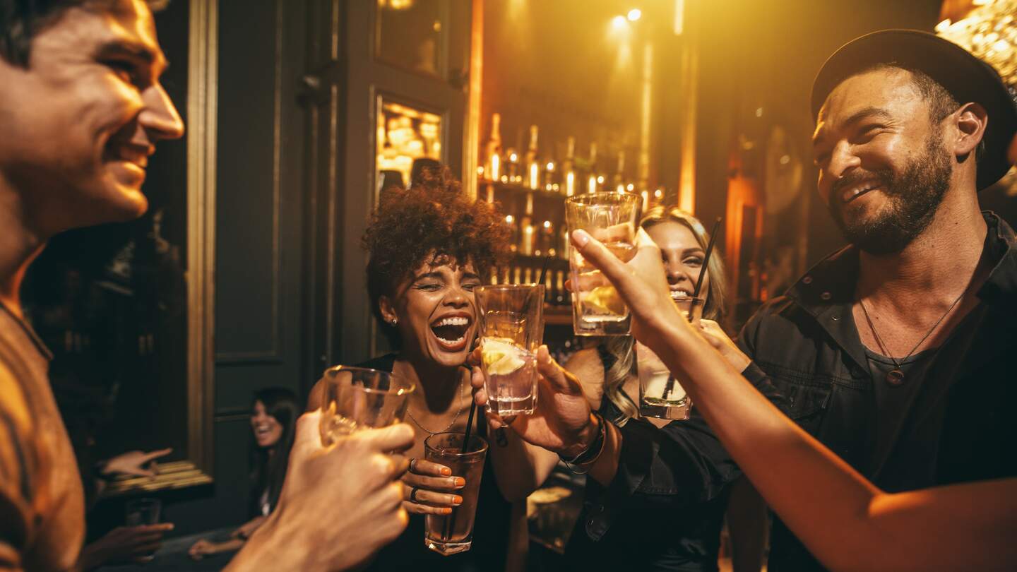 Junge Männer und Frauen genießen eine Party und trinken Cocktails in einem Nachtclub | © Gettyimages.com/jacoblund