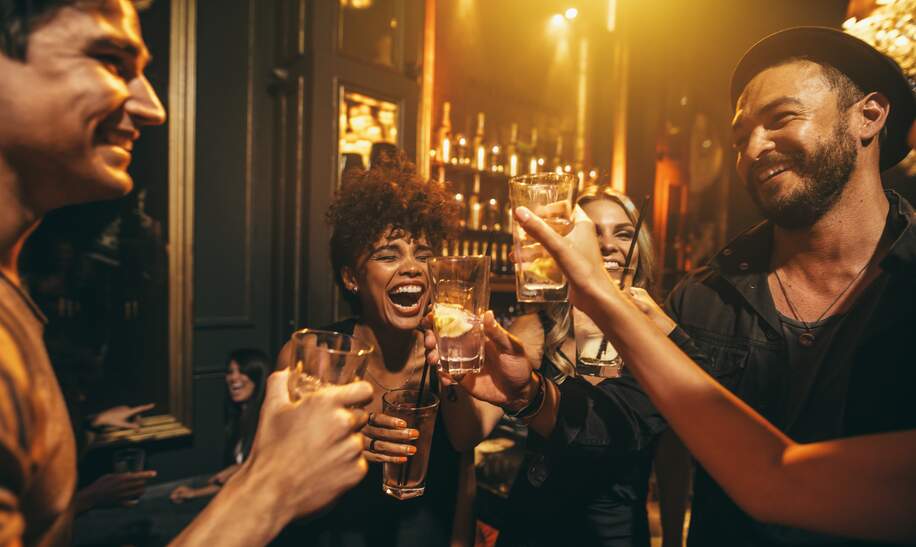 Junge Männer und Frauen genießen eine Party und trinken Cocktails in einem Nachtclub | © Gettyimages.com/jacoblund