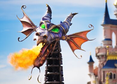 Paradewagen Maleficent in Form eines Drachen der Feuerspukt während der Parade Disney Stars on Parade mit dem Schloss von Disneyland® Park im Hintergrund | © Disney
