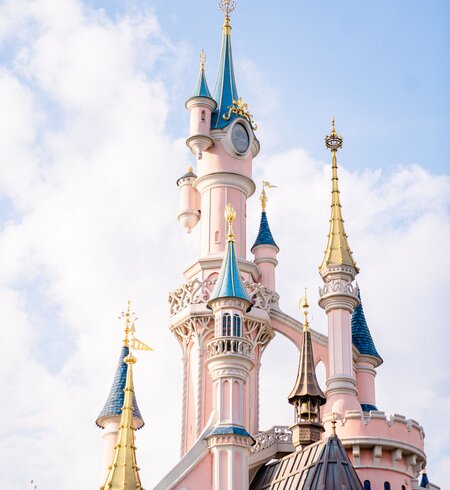 Das pinke Schloss Sleeping Beauty Castle in Disneyland® Paris mit blau strahlendem Himmel | © Disney