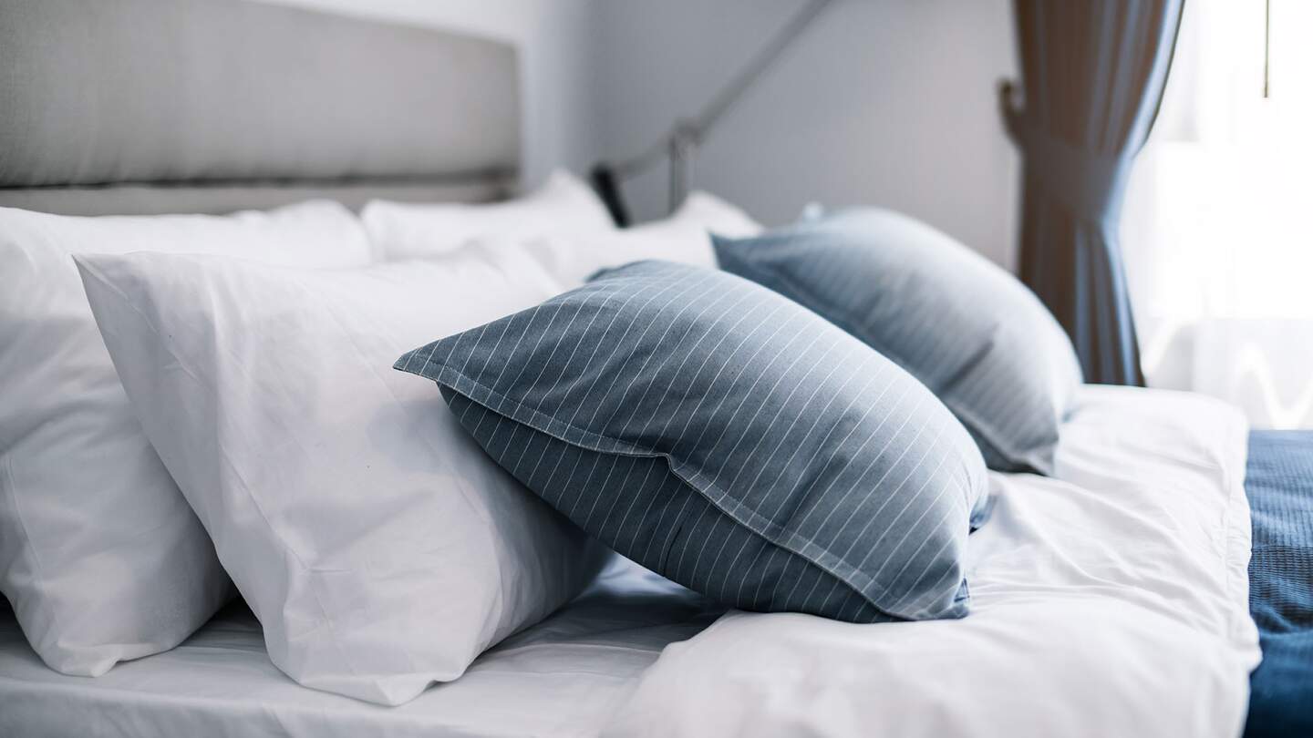 Nahaufnahme eines sauberen weißen Kissens und Bettwäsche in einem Hotelzimmer | © Gettyimages.com/whyframestudio