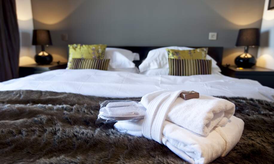Modernes Hotelzimmer mit Kingsize-Bett, auf dem Handtücher liegen | © Gettyimages.com/WILLSIE