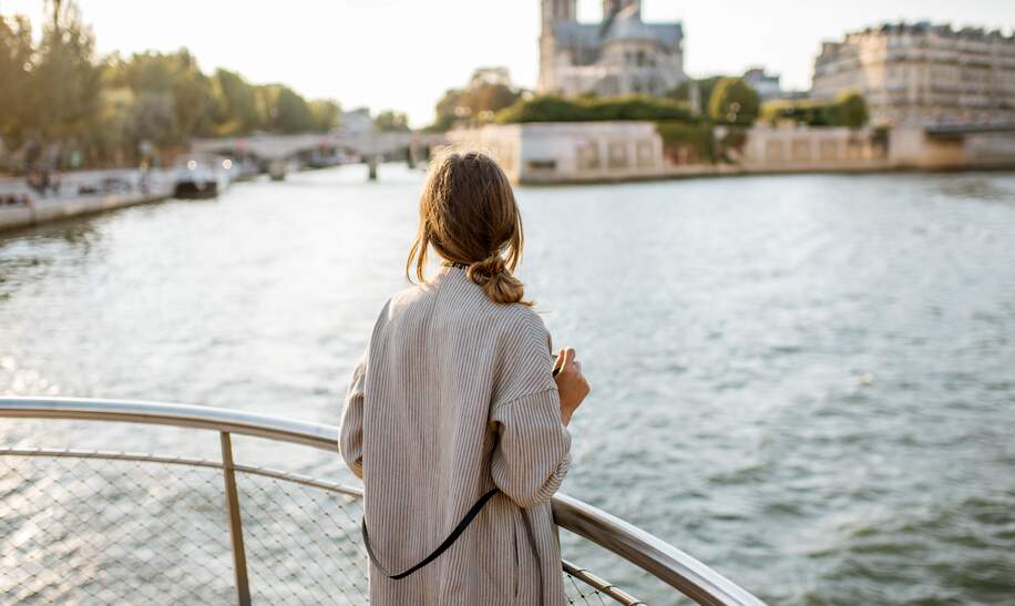 Frau geniesst den Landschaftsblick auf die Stadt Paris vom Boot aus | © Gettyimages.com/RossHelen