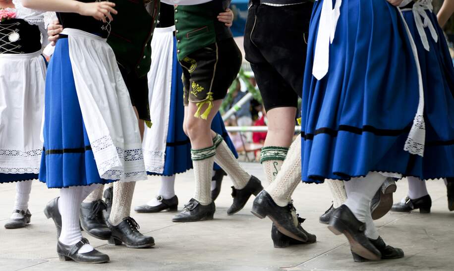 Bayerische Paare in Lederhose und Dirndl tanzen zu typisch bayerischer Blasmusik | © Gettyimages.com/sebastianjulian